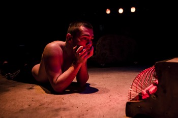  Bobbie (Jake Davies) lays on the floor propped up on his elbows. He stares into a three-bar electric heater which glows brightly. In the production, the heater is a visual representation of the boys' neglected dog. 