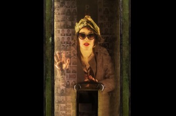 Amelie The Musical Production Image. Amelie (Audrey Brisson) inside a phonebox revealed through a semi-transparent window in the photobooth.