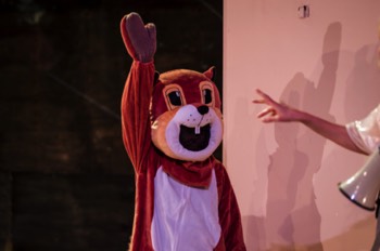 A person in a squirrel mascot costume waves.