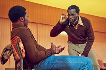 Jitney Production Image. Turnbo (Sule Rimi) leans over a seated Youngblood (Solomon Israel) confrontationally.