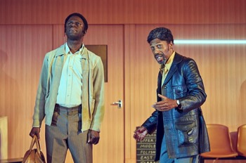 Jitney Production Image. Fielding (Tony Marshall) looks outwards whilst speaks to Philmore (Dayo Koleosho) who stands beside him with a full holdall.