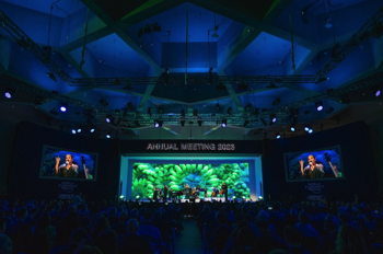A wide angle shot of the congress hall stage and ceiling, with full size video screen showing images of coral and the ceiling lit in deep blue