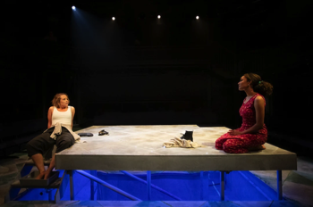 Flo (Jessica Clark) and Bel (Ruby Crepin-Glyne) sat on the stage, with the underside glowing in blue.