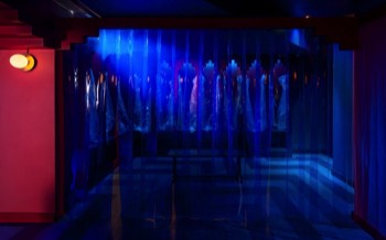 A cloakroom designed to look like cloister arches behind a wall of blue vinyl butcher curtains.